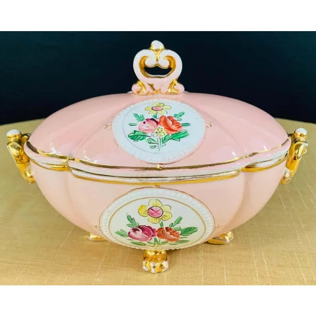 An exquisite and decorative Italian porcelain jewelry box. Hand painted in pink, gold and white with flower motifs, the...