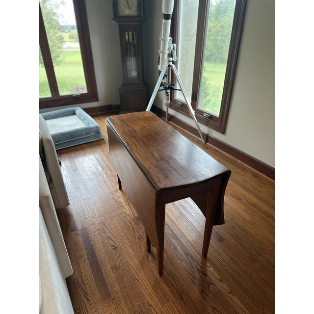 Graceful drop-leaf wood table with tapered legs, shaped leaves and contrasting line inlay in the Federal and Hepplewhite...
