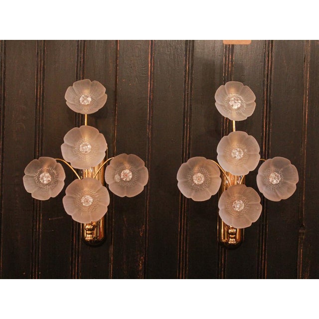 Pair of vintage gold-plated brass wall sconces with five arms topped with frosted glass flowers. Each sconce features a...