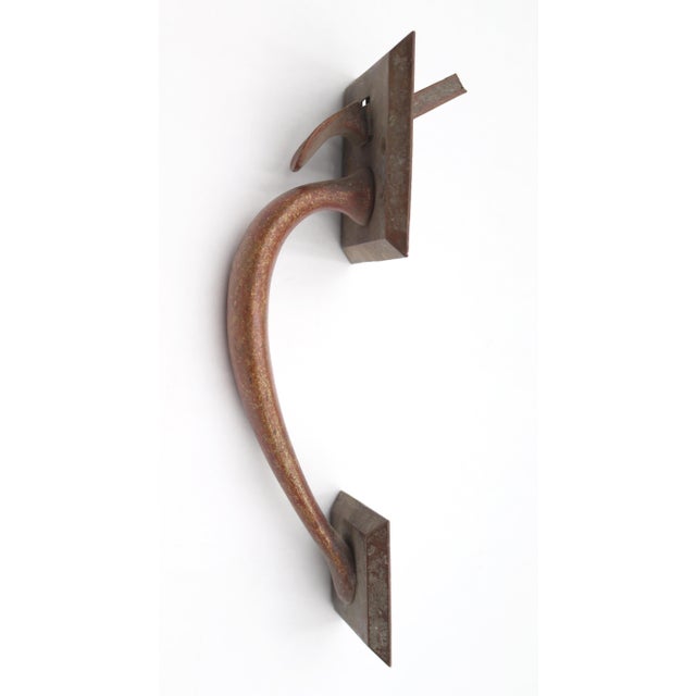 Vintage dark brass thumb latch door pull with a curved shaped handle and square plates. The original mounting screws are...
