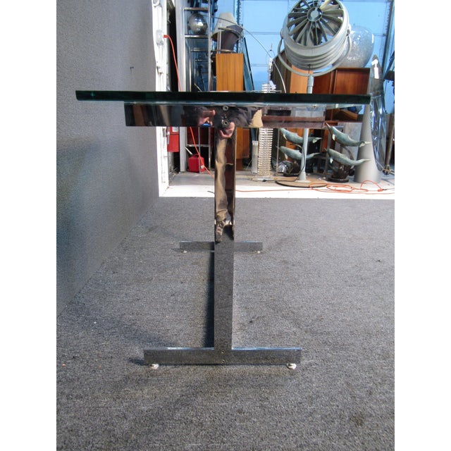 This elegant chrome and glass side table offers Mid-Century Modern style in the style of Milo Baughman. A thick glass top...