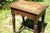 An antique English oak joint stool with a rich dark brown patina and visible grain, rectangular solid wood top, scalloped...
