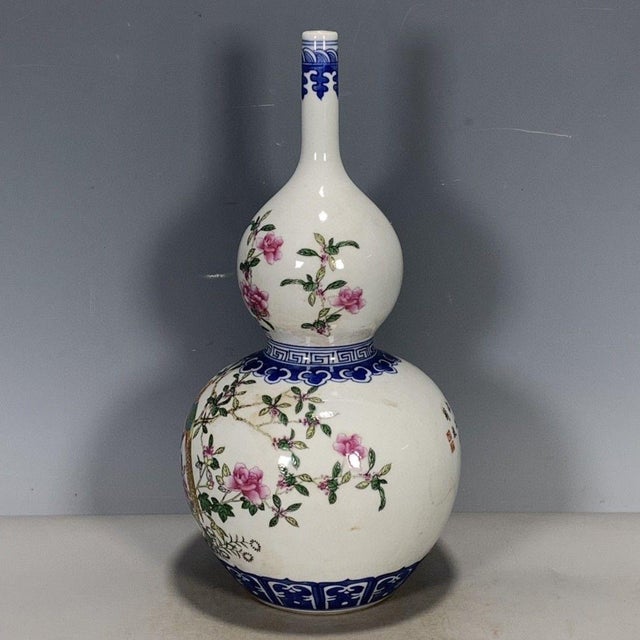 A beautiful Chinese porcelain double gourd vase. The vase features a white ground decorated with vibrant Famille Rose...