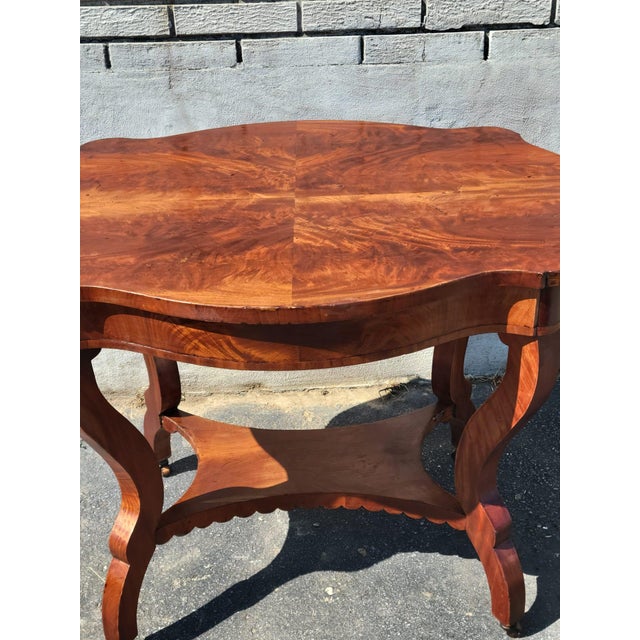 Beautiful vintage wooden side table featuring an elegant, decorative design with a warm reddish-brown wood finish. The...