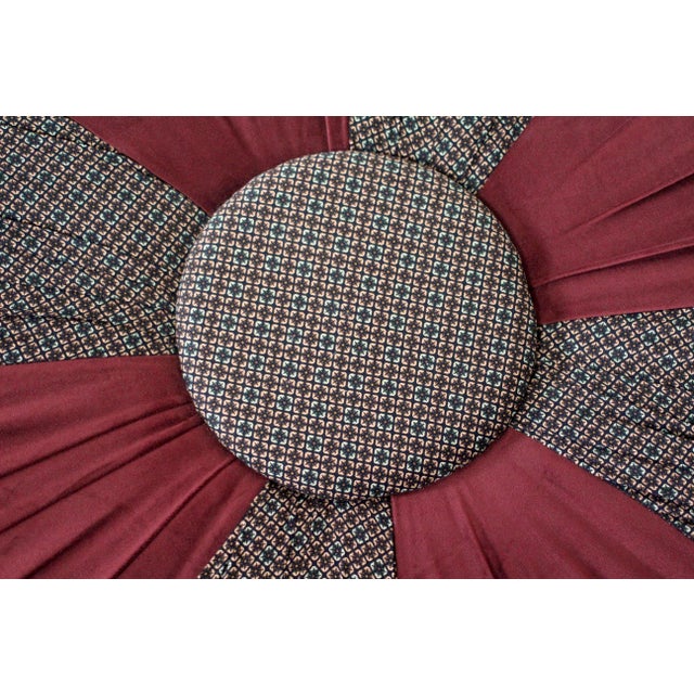 Upholstered massive ottoman on 4 wood legs with brass wheel. Large button in the middle with burgundy brown fabric...