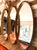 A glamorous Hollywood Regency statement mirror featuring three interlocking vertical oval panels set in a heavily ornate...