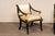 A French pair of black and gold armchairs, with eagle head carvings, from the mid 20th century. These mid-century chairs...