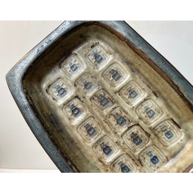 Rectangular stoneware dish from Royal Copenhagen. Decorated with lines/rows of Scarabs and colored in earthy glazes. Mark...