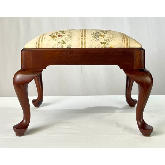 Queen Anne style footstool by fine furniture maker Henkel Harris. This stool features a solid mahogany frame with a rich,...