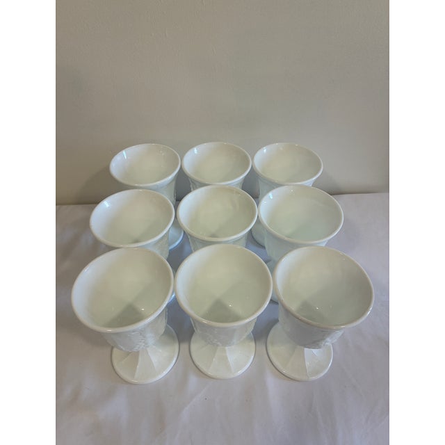 A beautiful set of nine vintage white milk glass pedestal goblets featuring an embossed grape and vine motif. Raised...
