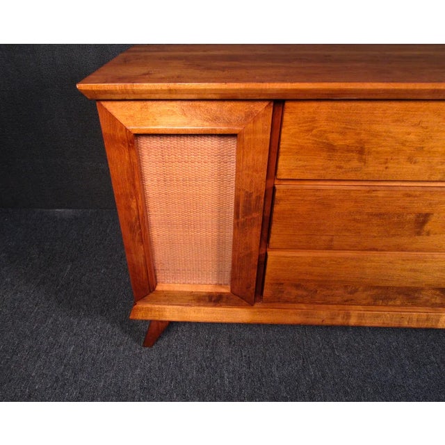 A vintage server full of Mid-Century Modern style, this piece can a brighten a room with its warm woodgrain and cane...