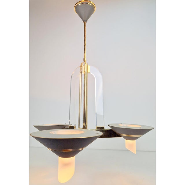 Modernist chandelier from the 1970s, crafted from brass and tempered acrylic iglass in the Regency style. This beautifully...