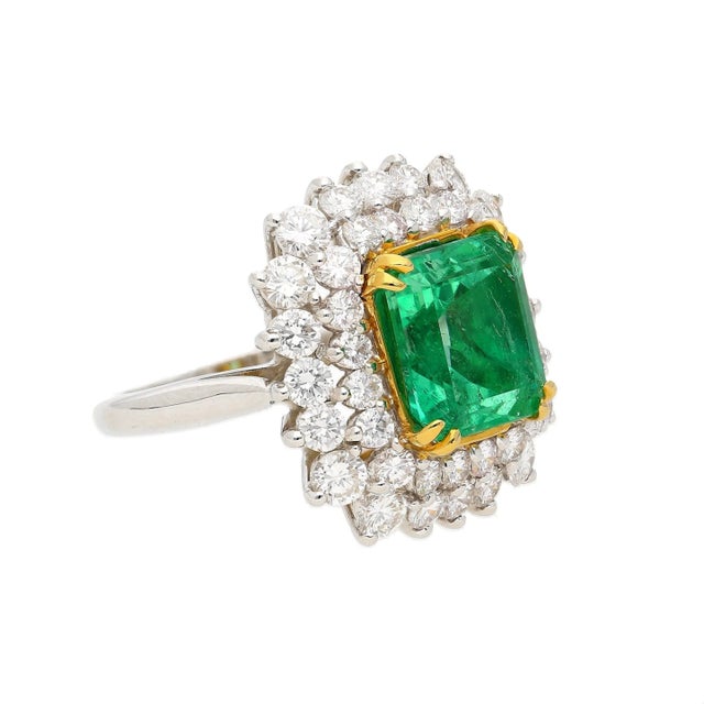 Centering a 4.30 Carat Emerald-Cut Insignificant Oil Colombian Emerald, framed by 40 Round-Brilliant Cut Diamonds totaling...