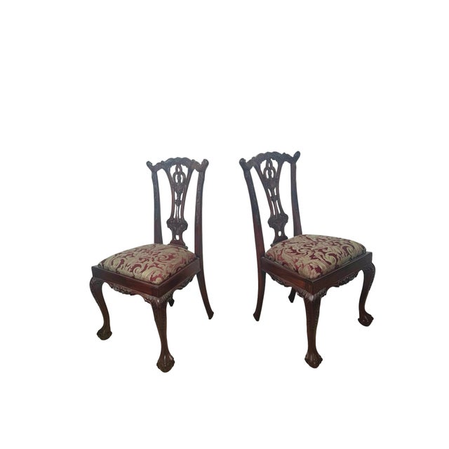 A striking set of four Chippendale-style mahogany dining chairs distinguished by elaborate carving, pierced splat backs,...