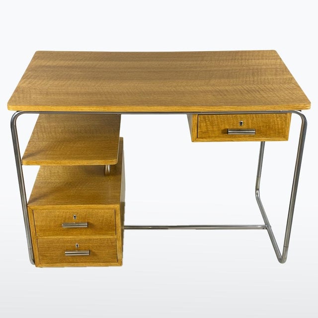 A refined functionalist desk combining a light chrome-plated metal frame with the warm appearance of oak veneer. Clean...