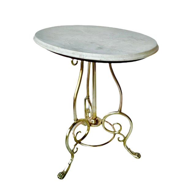 A fabulous vintage side table featuring a honed Carrara marble top supported by mahogany and resting atop a solid wrought-...