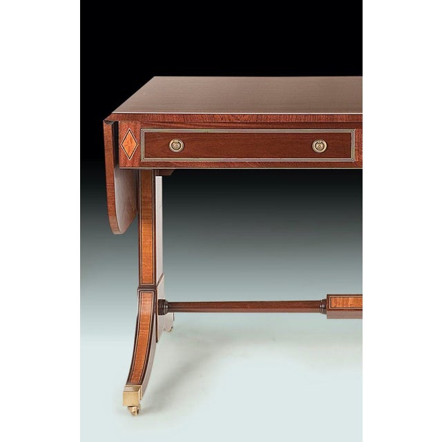 A handsome Regency sofa/writing table in Rosewood and Mahogany with ebonized stringing and Satinwood marquetry accents....