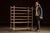 Tall rolling drying rack constructed with a painted wood frame reinforced by steel bracing and mounted on four swivel...