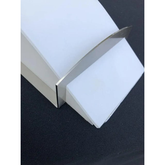 This wall light is made with high quality white satin glass and a sleek design nickelled metal structure. The glass part...