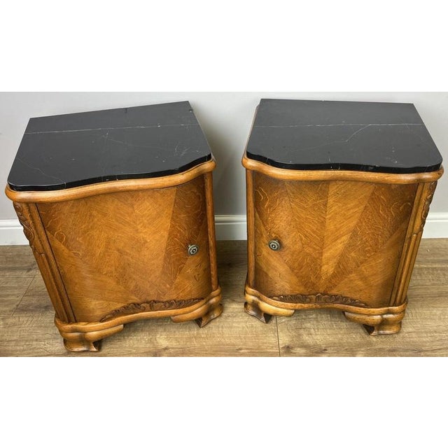 This elegant pair of Antique Art Deco bedside tables showcases striking black marble tops, beautifully curved fronts, and...