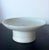 A small ceramic stemmed dish with high cylindrical foot in white glaze with a cobalt blue underglaze inscription in the...