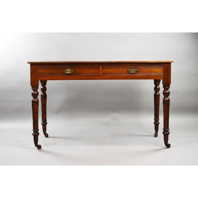An elegant Edwardian mahogany writing table of rectangular form with red leather top, standing on four finely turned legs...