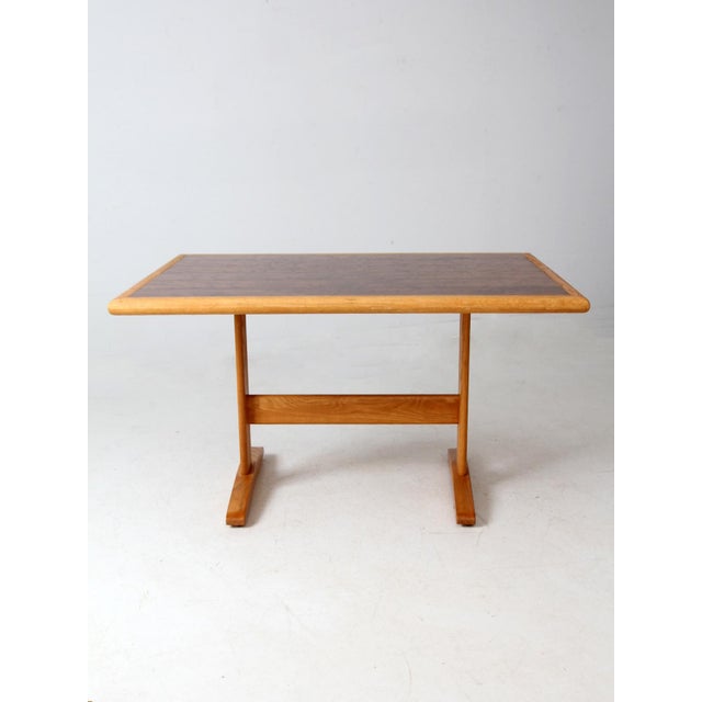 This vintage trestle table features a timeless design with a light natural frame and a darker planked inset tabletop that...