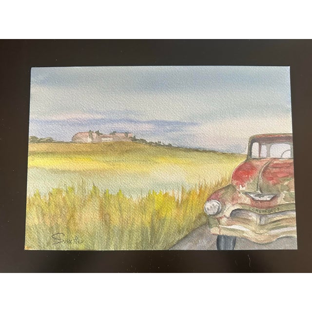 An old timey Chevy by the side of the road with a rolling landscape in the distance.