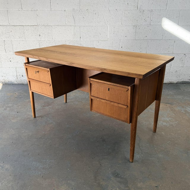 A rare Danish desk by Gunnar Nielsen, made in quarter-sawn oak with a substantial floating top raised above the frame on...