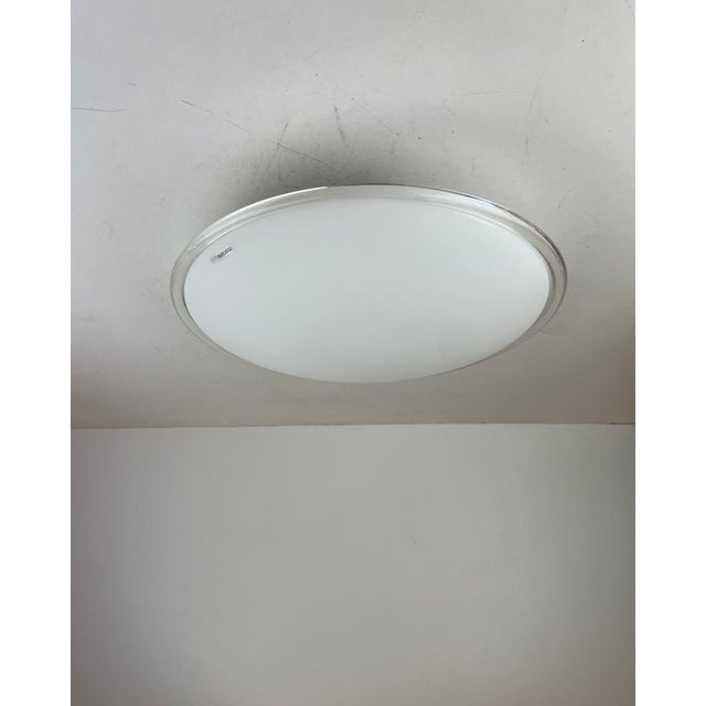 Elegant and minimalist flush-mount light made of a frosted murano glass diffuser with a transparent handmade rim and a...