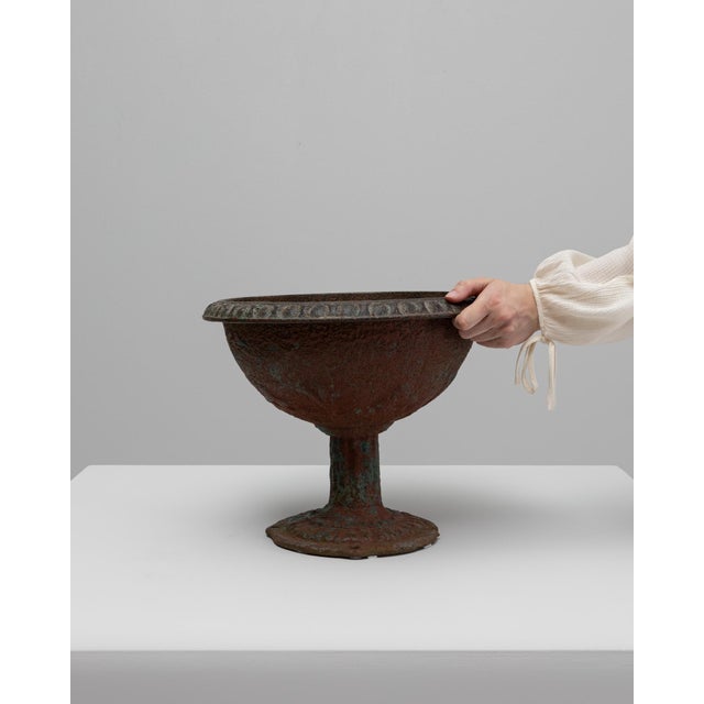 This 19th-century French cast iron planter features a classic footed form and richly weathered surface, embodying the...
