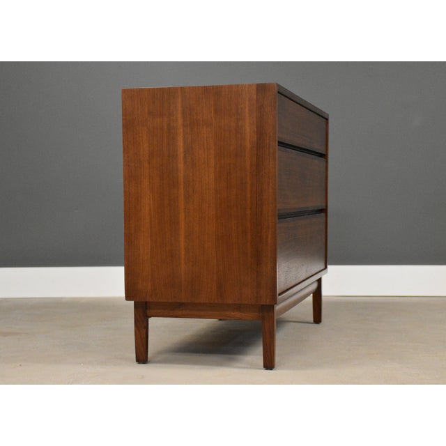 A mid century modern walnut dresser with rosewood drawer pull accents designed by Kipp Stewart for Directional by Calvin....
