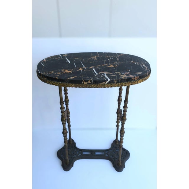 A substantial German oval marble console table with a black 'Porto' marble top and gold gilt brass or bronze base, circa...