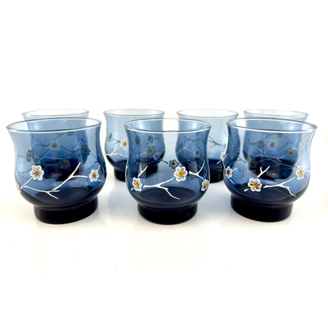 Set of eight vintage blue glass tumblers featuring delicate hand-painted floral branch motifs reminiscent of cherry...