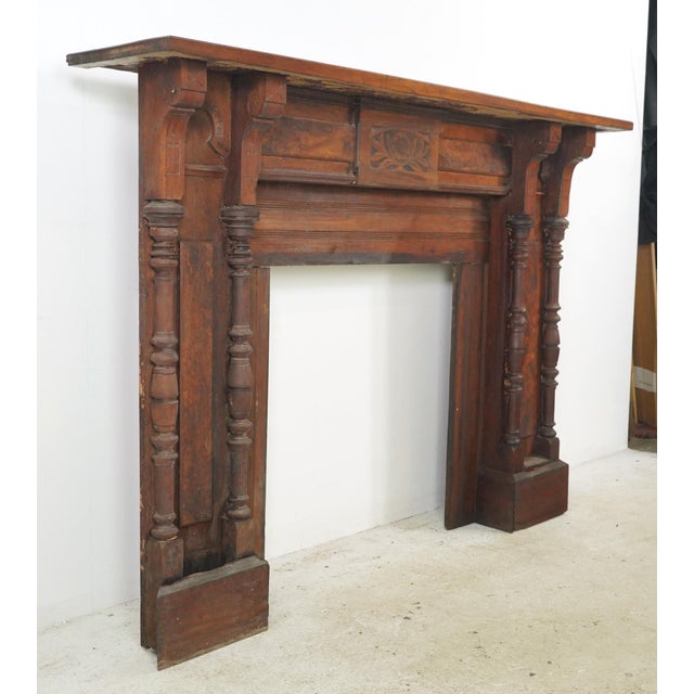 Antique Eastlake style wood fireplace mantel with a dark stain. It features an intricate design: a floral carving in the...
