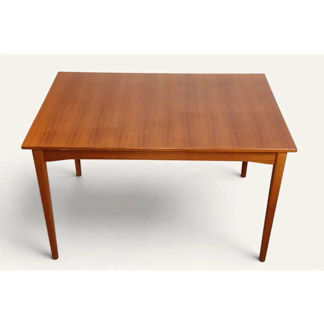 Elegant 1960s teak dining table in Scandinavian style. Its rectangular top with its warm grain rests on four tapered legs,...
