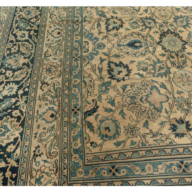 An early 20th century Persian Meshad carpet, the caramel field with an allover trellis of palmettes, cloudbands, and leafy...