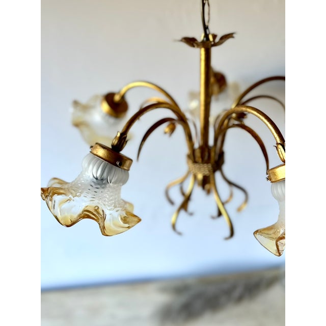 Vintage Italian chandelier featuring a gilt metal frame with floral and foliate decoration. The chandelier is fitted with...