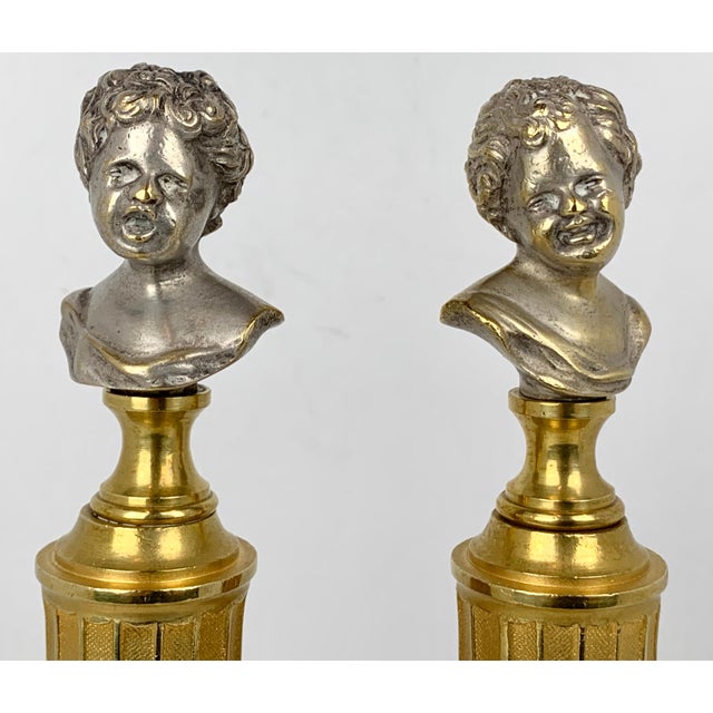 Pair of parcel-gilt bronze heads of crying babies on fluted bronze doré columns after Jean-Antoine Houdon. They have been...