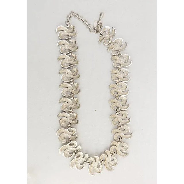This is part of Chairish’s Costume Jewelry assortment. Modernist rhodium plated textured squiggle links necklace with hook...