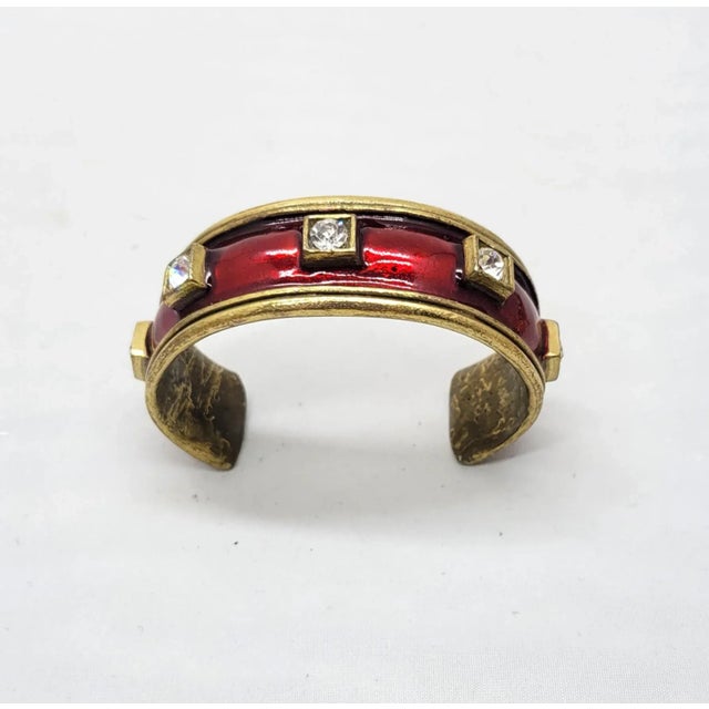 This is part of Chairish’s Costume Jewelry assortment. 1980s goldtone red enamel and round clear rhinestone slip on cuff...