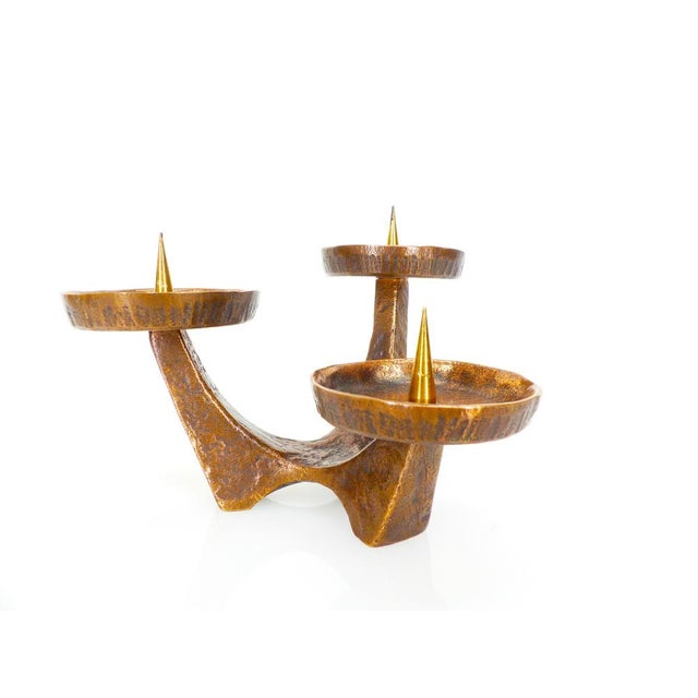 Vintage three-armed solid bronze candlestick, brutalist style, mounted on a tripod base. Each arm is topped with a...
