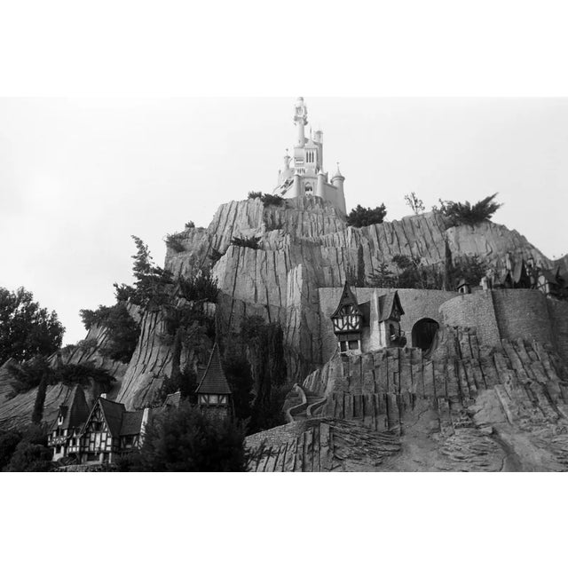 This black-and-white photograph offers a stunning view of Disneyland's Sleeping Beauty Castle, taken during the 1960s. The...