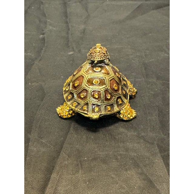 The Bejeweled Turtle & Baby Trinket Box is a charming and unique decorative accessory. Crafted from enamel painted metal...