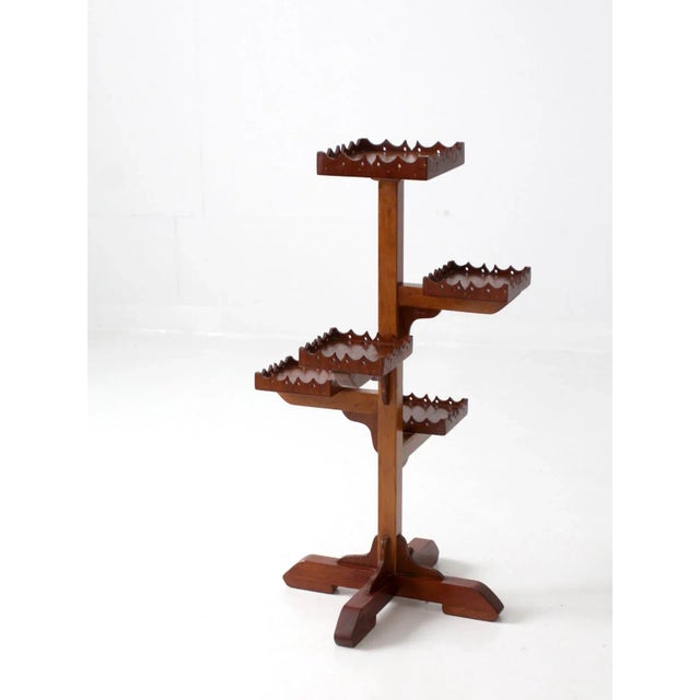 This is a vintage wooden plant stand. The five tiered stand features decorative cut-out lipped edges.