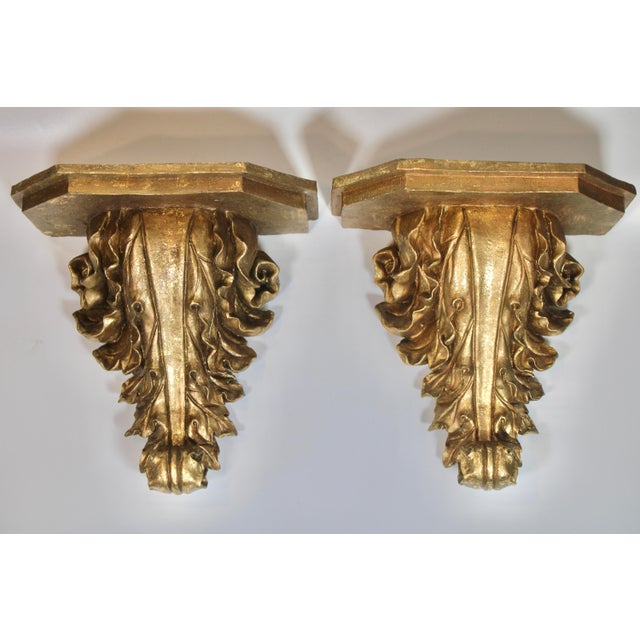 A stunning pair of large gold gilded resin acanthus leaf wall shelves. This is a bright and lovely sculptural pair. The...