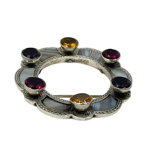 19th Century Scottish Brooch A round Scottish brooch with agate and glass stones in a floral shape. The silver is engraved...