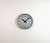 TCW post office wall clock was made in Netherlands during the 1960s. It features a grey iron frame, a metal dial, an...