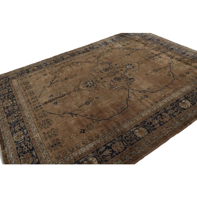 Hand-knotted in wool, this 8x11 antique Turkish Isparta rug, circa 1920-1930, enjoys rich brown and navy blue tones in...