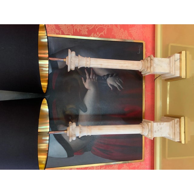 A spectacular pair of monumental marble ionic column lamps with gilt wooden bases and black silk shades with gold foil...